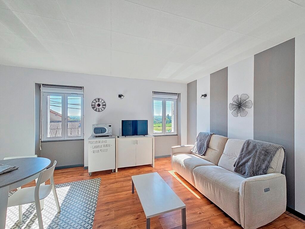 Salon lumineux avec canapé et télévision dans l’appartement Le Tilleul