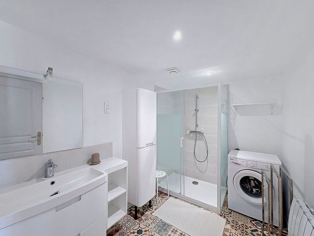 Salle d’eau avec douche et lave-linge de l’appartement Le Cèdre
